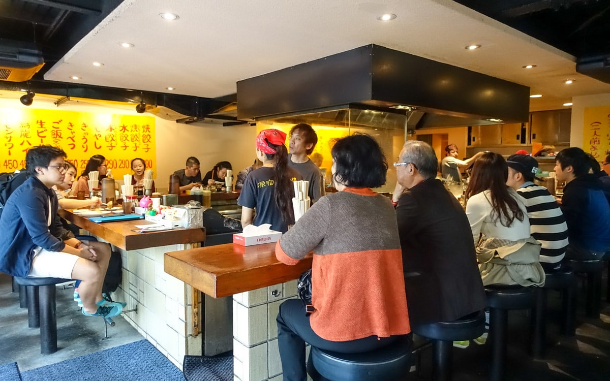Bar wrapping around the central open kitchen, Harajuku Gyoza Lou, Tokyo, Japan