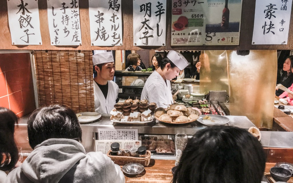 Chefs grilling meats over charcoal, Kushiwakamaru Honten, Tokyo, Japan