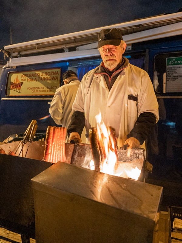 Grilling kielbasas over an open flame, Blue Nysa Van (Kiełbaski z Niebieskiej Nyski), Kraków, Poland