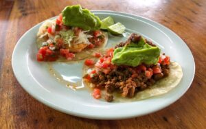 Fully dressed shrimp taco on the left, sausage taco on the right