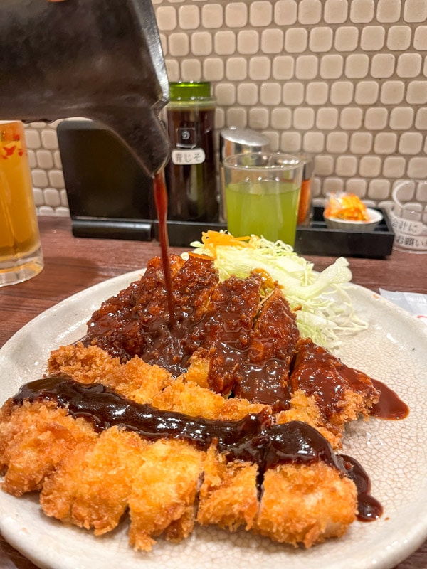 Miso sauce being poured over the pork cutlet, Misokatsu Yabaton, Nagoya, Japan